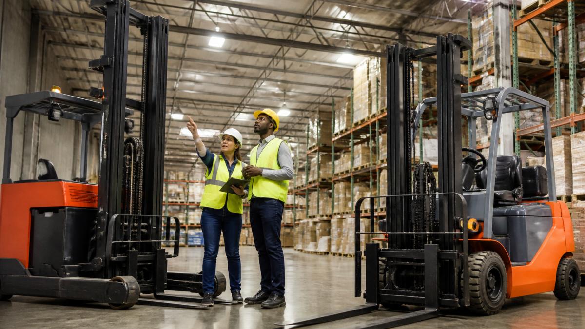 Supervisor and operator discussing load handling with reach and counterbalance forklifts in a warehouse